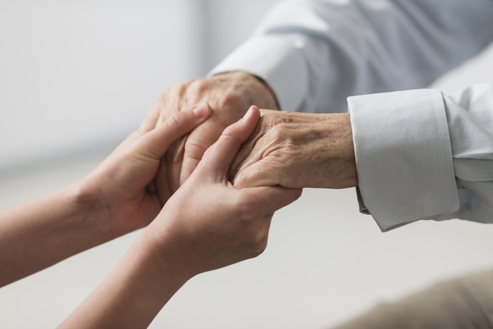 A Pluto BV care worker gently holding a client's hands in both of her own